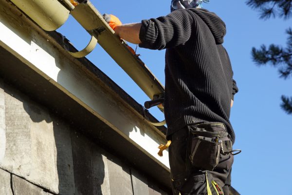 A low angle shot of a construction worker working and fixing a roof